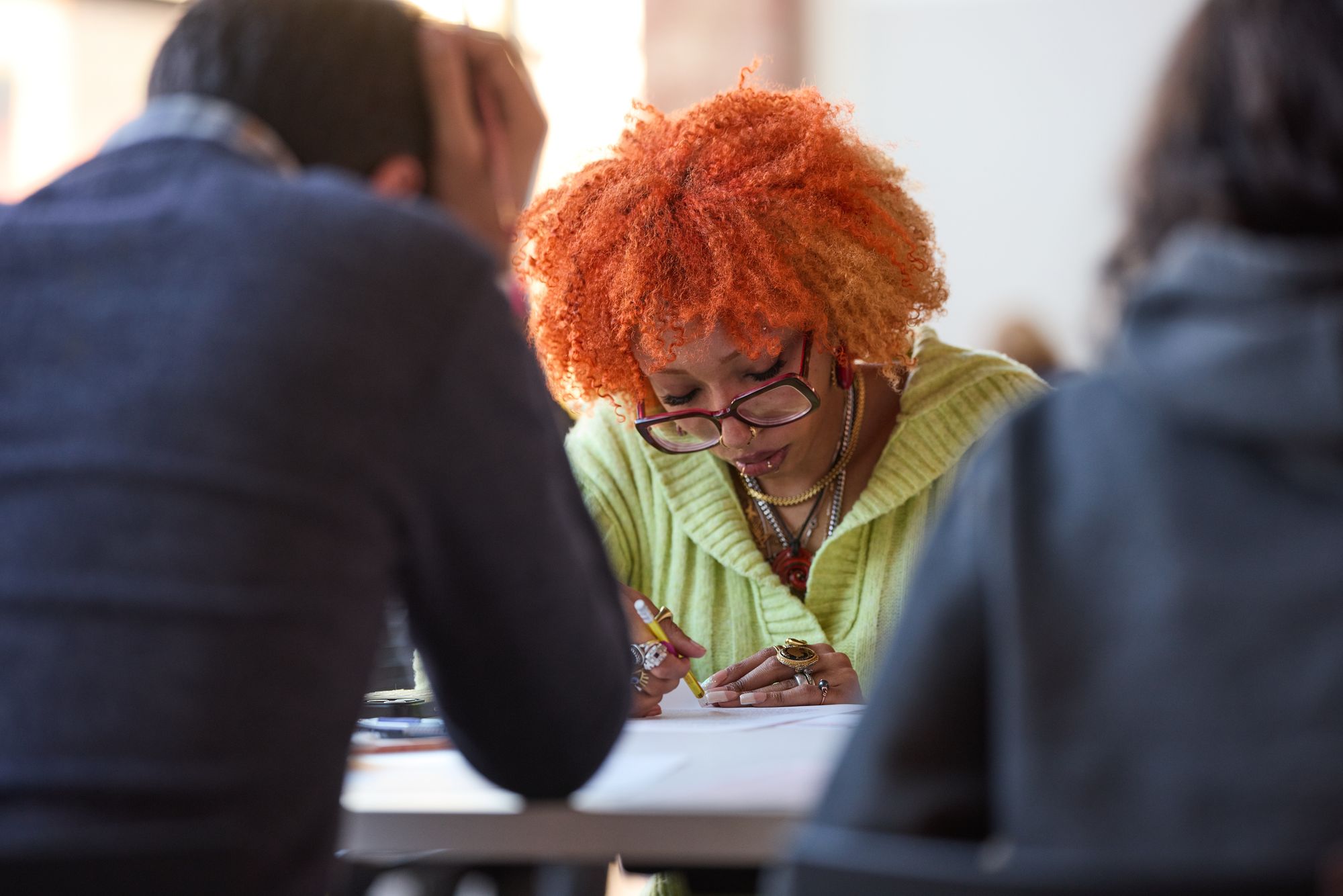 An attendee with a brightly-colored hairstyle and outfit works on the sheet.